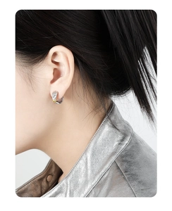 Detailed side view of model wearing a bicolor textured knot earring in silver and gold