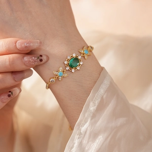 Détail d'un bracelet vintage doré avec pierre ovale verte et accents de zircon