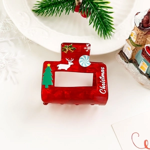 Detail view of red Christmas hair claw clip with festive tree and reindeer patterns