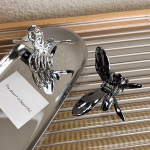 Detailed shot of 3D butterfly hair claws in polished silver and sleek black metal finish