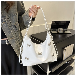 Primo piano di una borsa a spalla bianca con farfalle d'argento in un ufficio moderno