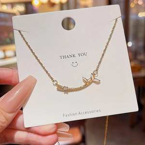 Detail of gold whale tail pendant with white drip oil and zircon inlay on a display card