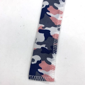 Detailed macro view of camo pattern webbing with precise white machine stitched edges