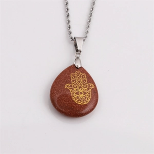 Detail of Hamsa Hand engraved on teardrop Goldstone pendant with silver twisted chain
