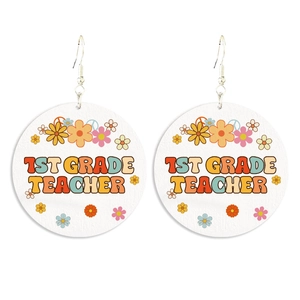 Close-up of circular wooden earrings featuring 1st Grade Teacher text and floral motifs