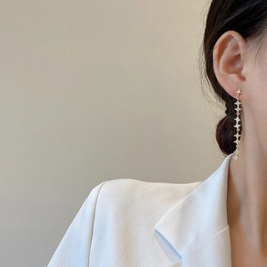 Elegant long gold star earrings with sparkling zircon dangles worn by a female model