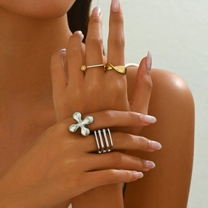 Close-up of stacked gold and silver titanium rings featuring floral and twisted textures
