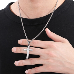 Close-up of sparkling diamond-encrusted silver cross pendant on a model wearing black