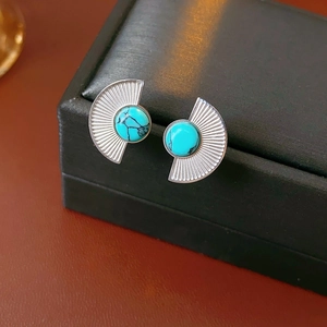 Macro view of fan-shaped turquoise earrings with silver metal on a leather jewelry box