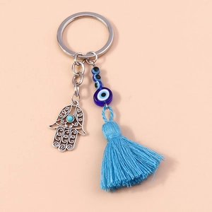 Detail of silver Hamsa Hand keychain with blue Evil Eye bead and decorative silk tassel