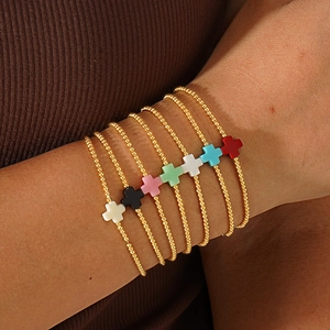 Set di sette bracciali di perline dorate con ciondoli a croce colorati indossati al polso
