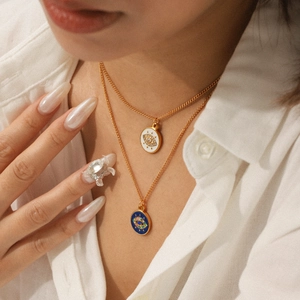 Detail of layered gold-plated necklaces featuring blue and white evil eye pendants with rhinestones
