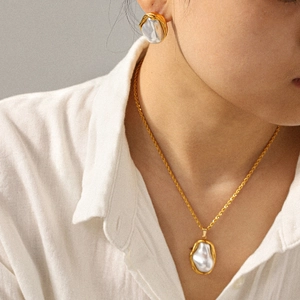 Close-up of golden irregular Baroque pearl necklace and stud earrings on a model