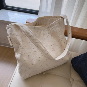 Dettaglio della borsa tote in tela crema con puntini colorati ed etichetta laterale