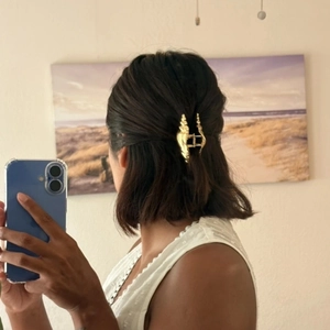 Detailed mirror view of a gold shell-shaped metal hair claw clip in a half-up hairstyle