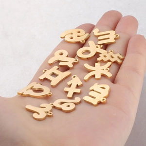 Golden 15mm stainless steel zodiac charms held in hand to show scale and shiny finish