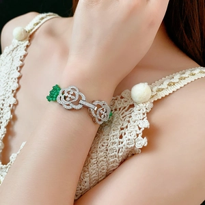 Close-up of silver Ruyi lock bracelet with clear zircon inlay and green bead tassel charm
