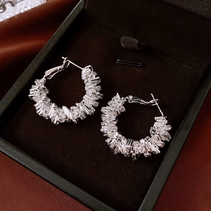 Détail de boucles d'oreilles géométriques argentées serties de zircons rectangulaires