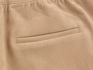 Détail du tissu en maille kaki avec une poche passepoilée renforcée et des coutures précises