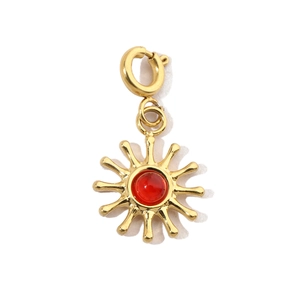 Macro detail of sunburst charm with red gemstone and golden spring clasp connector