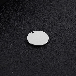 Macro view of polished silver stainless steel round pendant on textured black surface