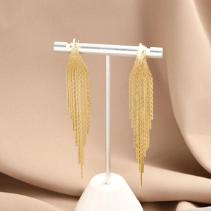 Close-up of golden long tassel earrings with tiered metal chains and embossed texture