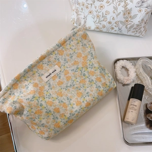 Detail of floral canvas makeup pouch with 'simple wish' label on a warm aesthetic setting