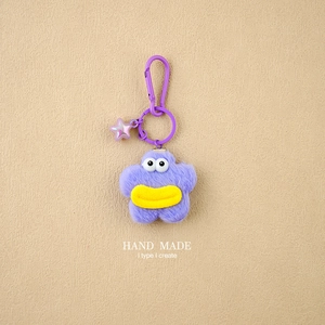Detail of purple star plush keychain with yellow lips and pink translucent charm