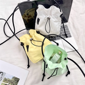 Tre mini borse a tracolla con coulisse in bianco, giallo e verde su una scrivania