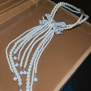 Détail du collier de perles multicouche avec pendentif nœud brillant et longues franges