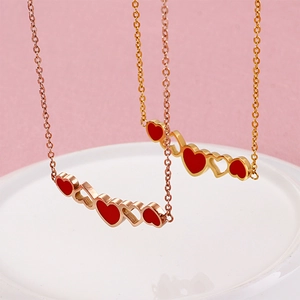 Rose gold Roman letter necklaces with red heart pendants displayed on a ceramic tray