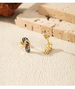Macro detail of silver flip-flop earrings with colorful zircon stones on beach stones