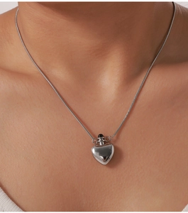 Close-up of polished silver heart pendant on a snake chain necklace worn by a model