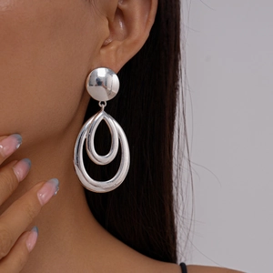 Close-up of geometric hollow drop earrings in silver finish worn by a professional model