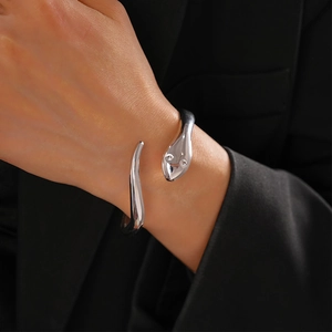 Detail of silver snake-shaped open cuff bracelet worn over a chic black blazer sleeve