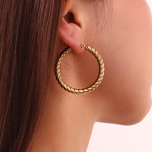 Detail of 18K gold plated twisted rope hoop earring on female model earlobe