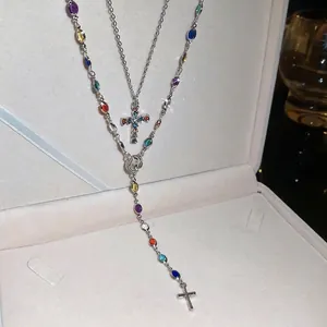 Double-layered silver necklace with rhinestone cross and religious icons in jewelry box