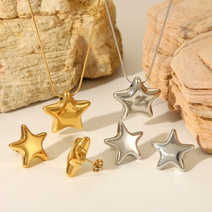 Polished gold and silver star necklace and earrings set on natural stone background