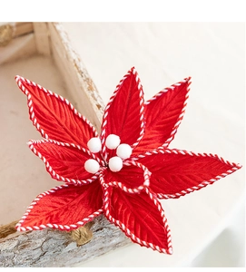 Nahaufnahme einer künstlichen Weihnachtsblume aus rotem Samt mit weißen Pompons