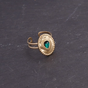 Close-up of golden oval ring with green teardrop stone and beaded relief details
