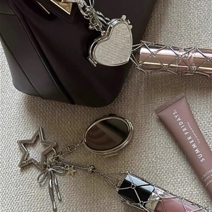 Silver lipstick pouch keychain with star and heart charms on a leather handbag accessory