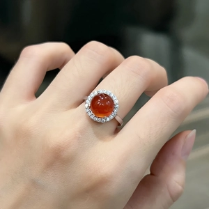 Close-up of a silver ring with a round orange chalcedony stone and small white diamonds