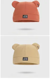 Détail du bonnet d'hiver avec oreilles d'ours, anneau en métal et écusson à lettres
