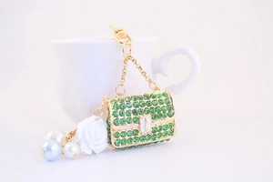 Macro detail of a green rhinestone handbag keychain with white rose and pearl accents