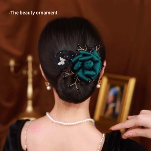 Detail of dark green silk rose hair pin with diamond butterfly on elegant hair bun