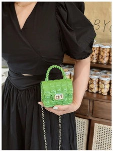 Close-up of quilted green jelly bag with gold chain strap and metal turn-lock closure