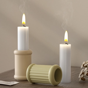 Detail of minimalist beige pillar and green striped resin candle holders on wooden surface