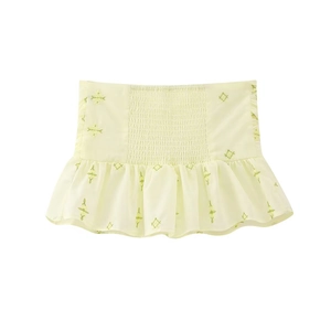 Détail d'un haut court jaune pâle avec broderies vertes et taille élastique plissée