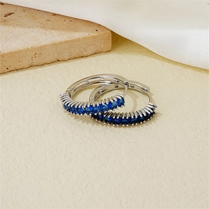 Elegant silver hoop earrings with square blue zircon stones on a silk fabric background