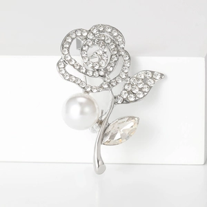 Detailed macro view of silver rose brooch with sparkling crystals and a white pearl